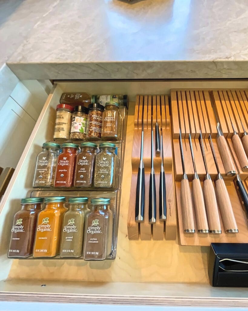 Same spice drawer after Simply Luxe organizing, with spices lined up on tiered inserts beside an in-drawer knife block, San Diego