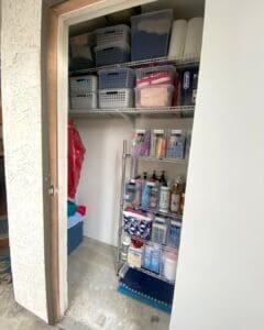 Same Orange County storage closet after decluttering, with labeled clear bins, gray baskets and a rolling wire rack of sorted supplies and an open floor