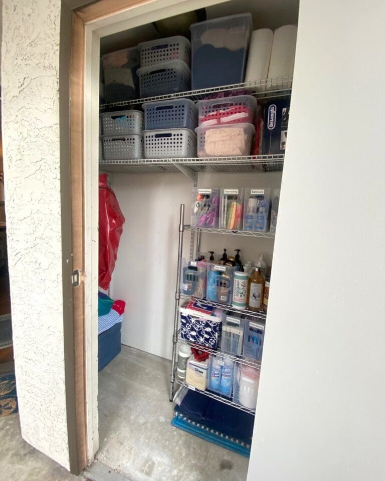 Same Orange County storage closet after decluttering, with labeled clear bins, gray baskets and a rolling wire rack of sorted supplies and an open floor