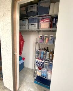 Same storage closet after decluttering, with a metal wire rack, labeled bins and supplies sorted by type