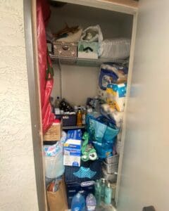 Storage closet before decluttering, packed floor to ceiling with paper goods, bags and cleaning supplies