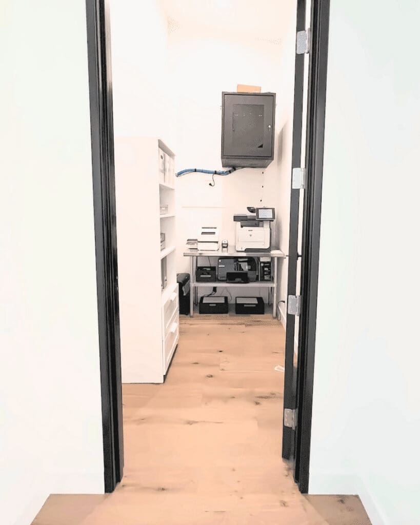 Commercial office supply room after organizing, with shelving, printers on a clear station and an open floor