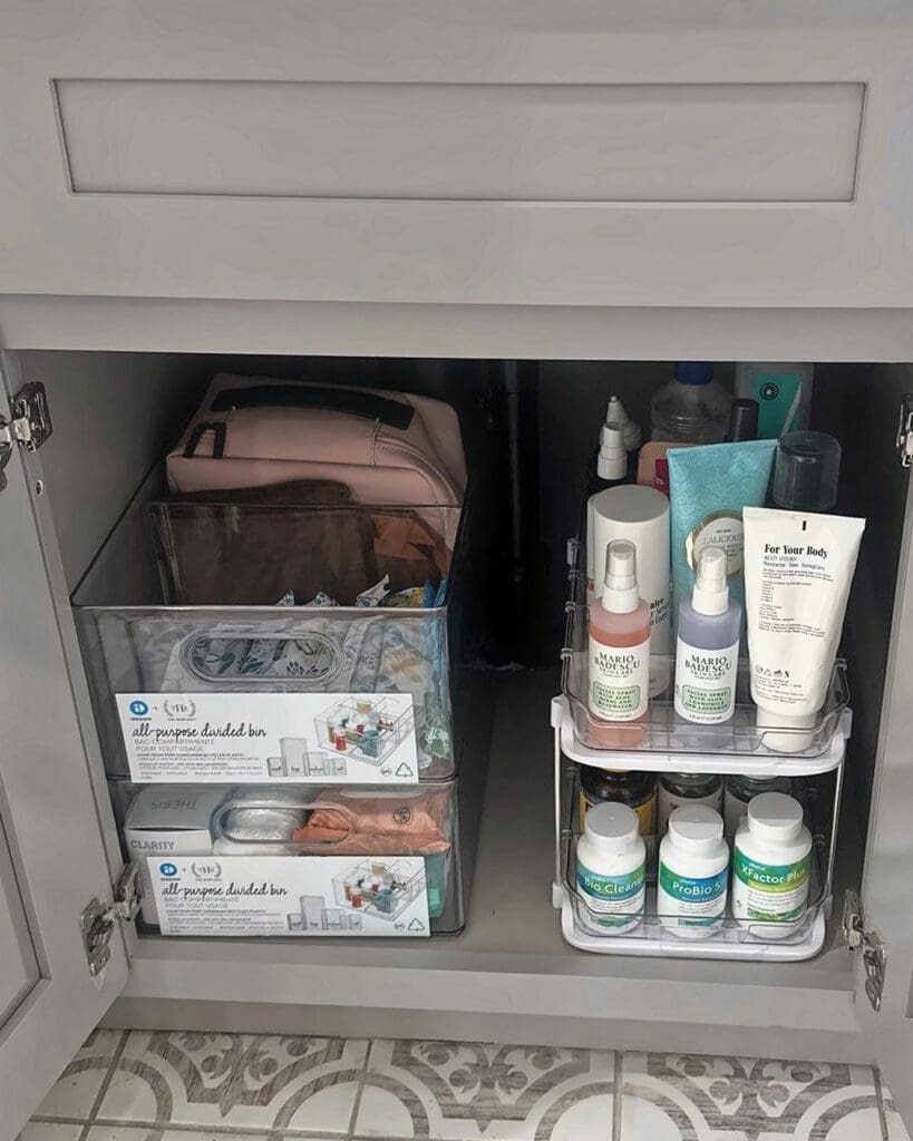 Bathroom under-sink cabinet after organizing, with toiletries sorted into clear labeled bins, Costa Mesa