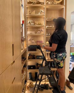 Simply Luxe organizer on a step stool unpacking shoes onto a built in shoe wall, San Diego