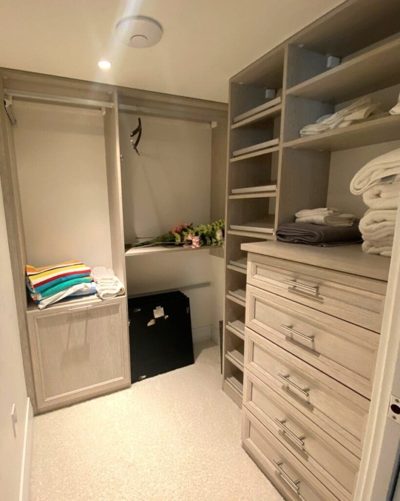 Walk-in closet before styling, with empty custom shelving and a few folded towels