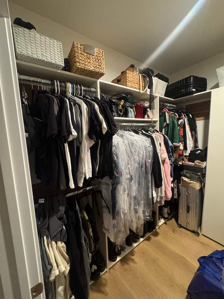 Walk-in closet in Los Angeles before organizing, with mixed hanging clothes and crowded shelves