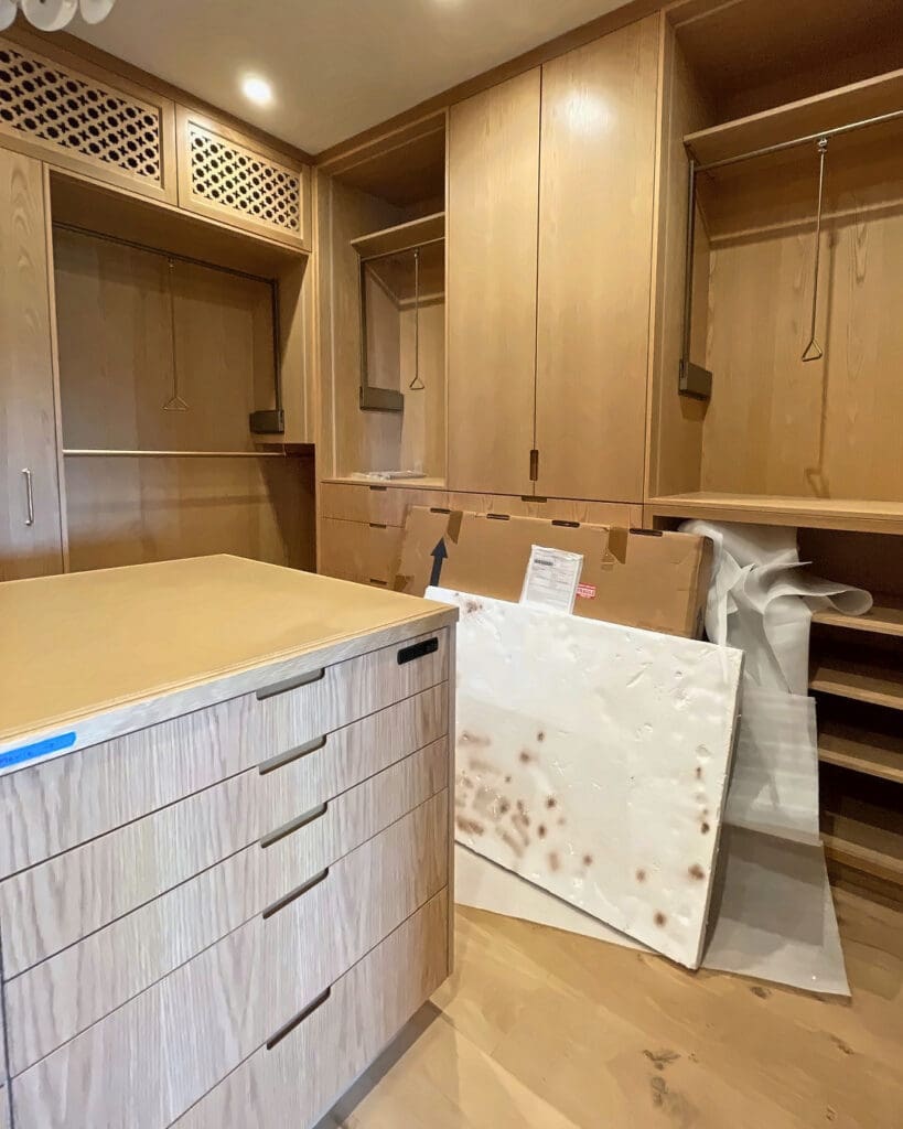 Custom walk-in closet on move-in day, with empty cabinets and a rug leaning beside the drawer island, San Diego
