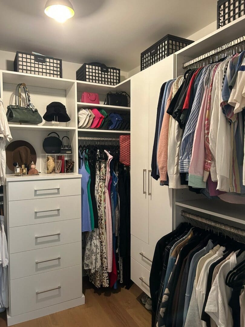 Organized walk-in closet corner with bins, handbags and color-sorted hanging clothes, Woodland Hills