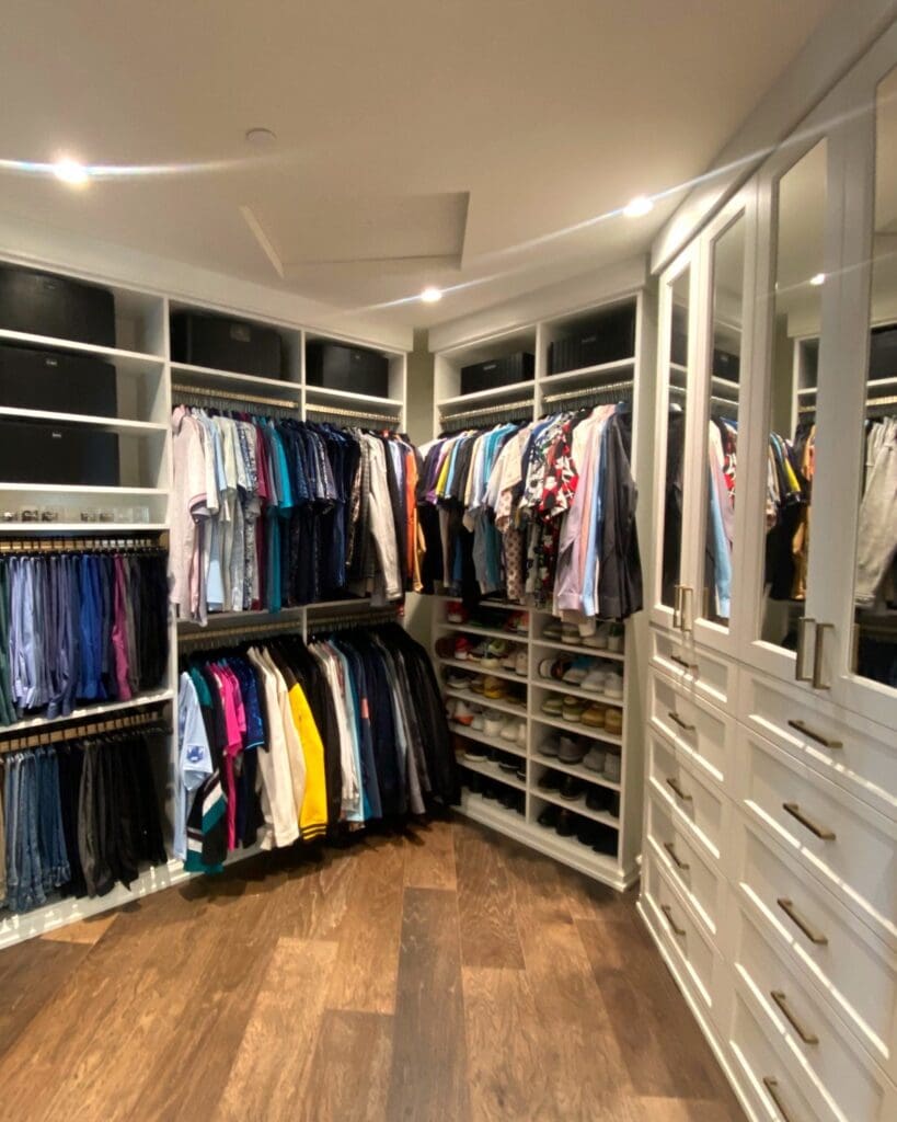Same walk-in closet after the makeover, with shirts hung by color, shoes on the shelves and glass front cabinets, San Diego
