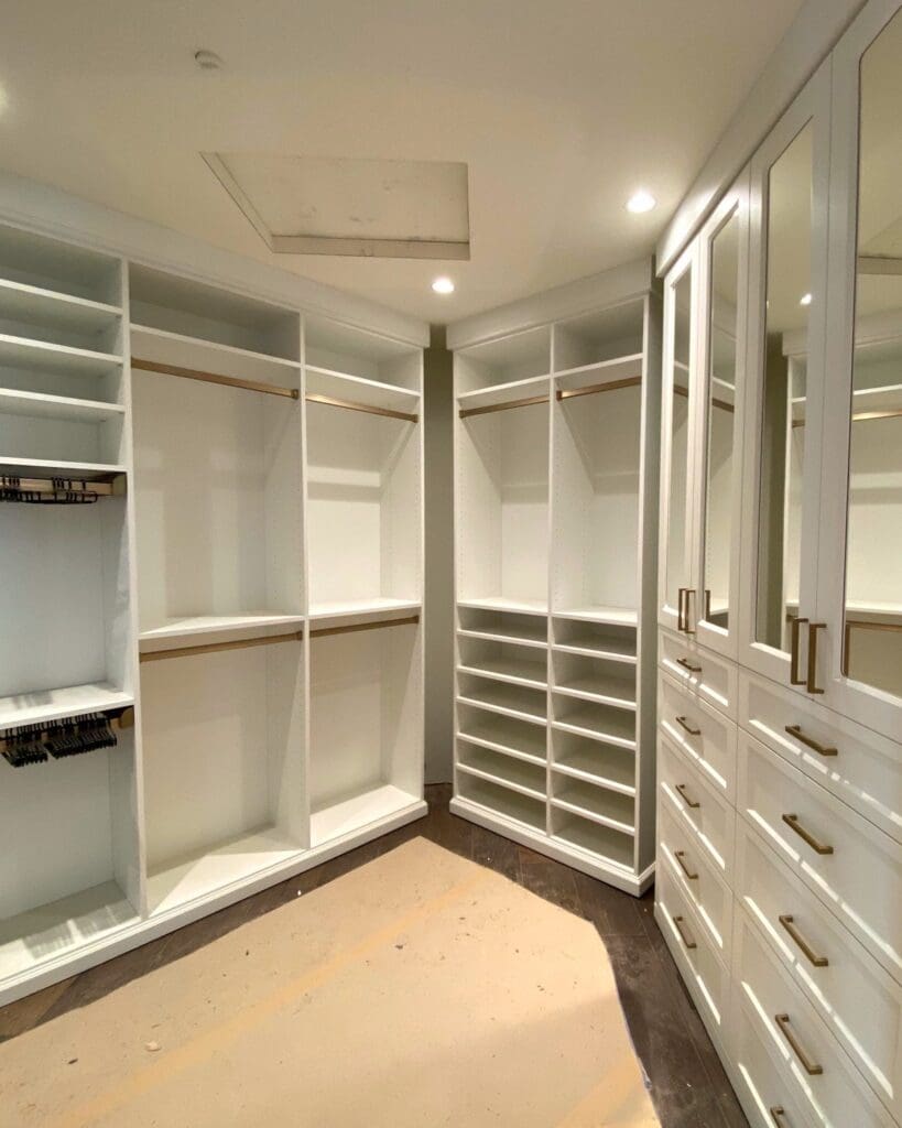 Walk-in closet before the makeover, with empty white shelves and drawers and bare floors, San Diego