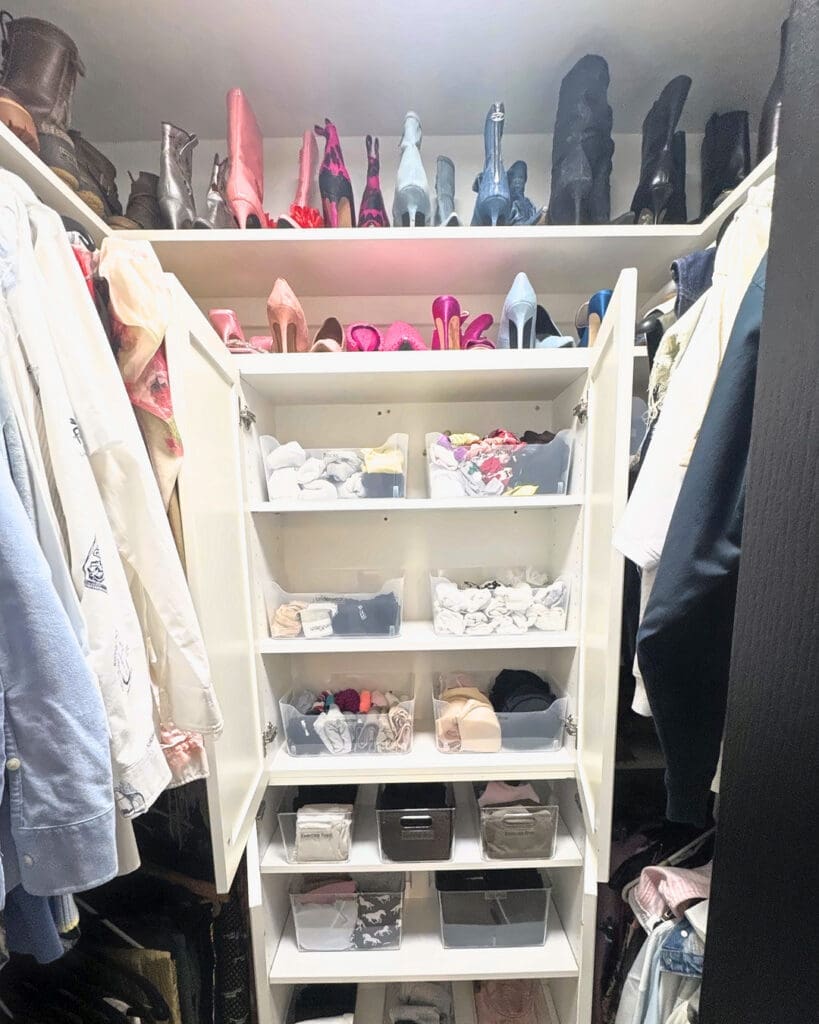 Walk-in closet after Simply Luxe organizing, with shoes displayed on the top shelves and folded items sorted into clear bins, Newport Beach