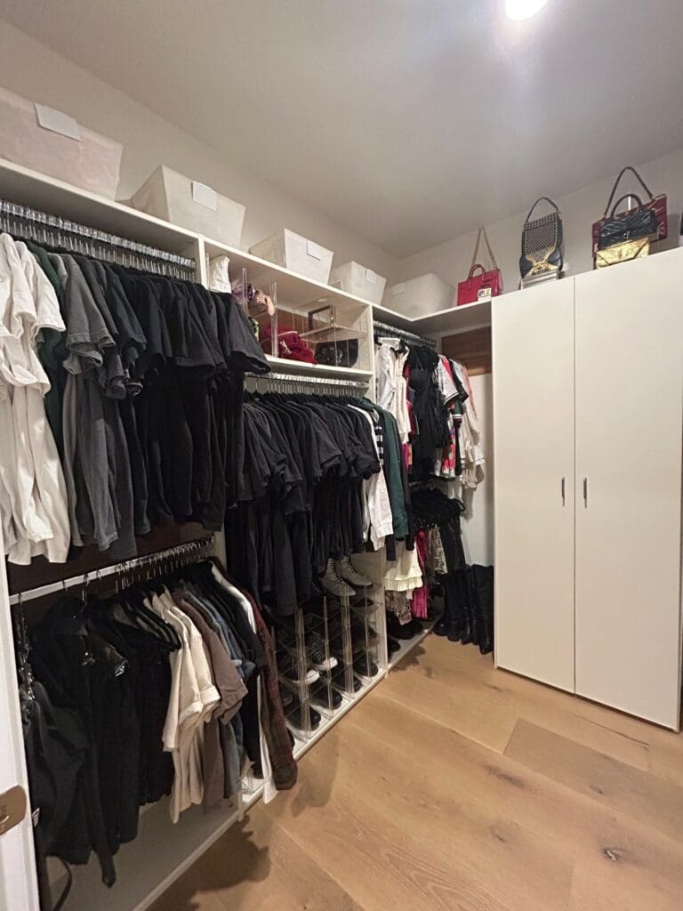 Katie Maloney's celebrity closet in Los Angeles after organizing, with black and white clothes hung by type and bags displayed up top